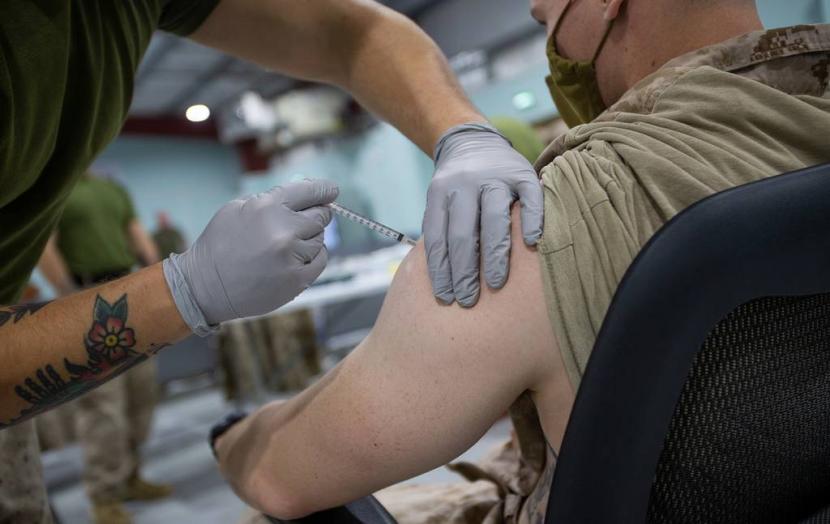 Petugas kesehatan sedang menyuntikkan vaksin kepada personel militer Amerika Serikat.