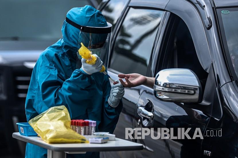 Petugas kesehatan yang mengenakan pakaian pelindung dan sarung tangan melakukan uji cepat penyakit virus korona di Palembang, Senin (4/5).