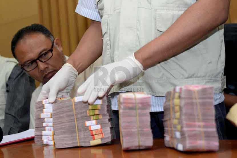 Petugas KPK menunjukan barang bukti uang dalam pecahan Rupiah dan Dolar Singapura hasil operasi tangkap tangan Gubernur Riau Annas Maamun di Gedung KPK, Jakarta, Jumat (26/9).(Republika/ Wihdan)