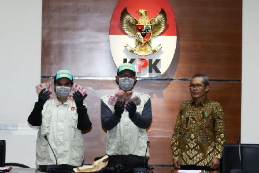 Petugas KPK menunjukkan barang bukti disaksikan oleh Wakil Ketua KPK Alexander Marwata (kanan) seusai memberikan keterangan pers terkait Operasi Tangkap Tangan (OTT) kasus dugaan suap jaksa di Gedung KPK, Jakarta, Selasa (20/8/2019). 