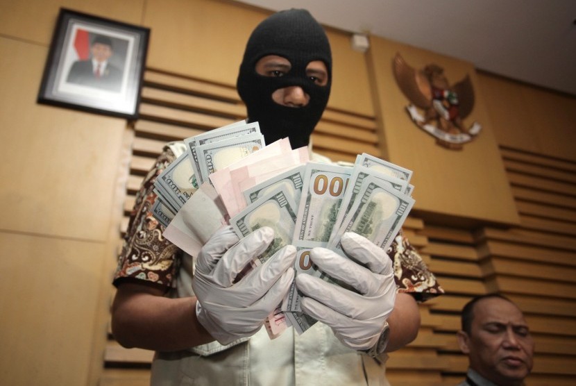 Petugas KPK menunjukkan uang dolar AS dan dolar Singapura yang merupakan barang bukti hasil OTT (Operasi Tangkap Tangan) di Gedung KPK, Jakarta, Jumat (10/7). 