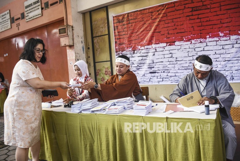 Petugas KPPS membantu warga yang akan memberikan hak suaranya di TPS 004 di Kelurahan Cibadak, Kecamatan Astanaanyar, Kota Bandung,