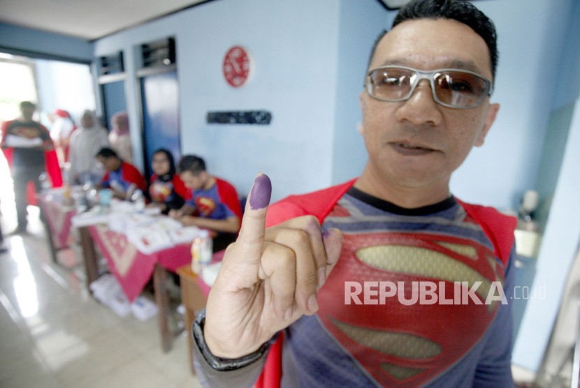 Petugas KPPS menunjukan jari seusai memberikan hak suaranya di TPS 072 Mekarjaya yang bertemakan superman di Depok, Jawa Barat, Rabu (17/4/2019).
