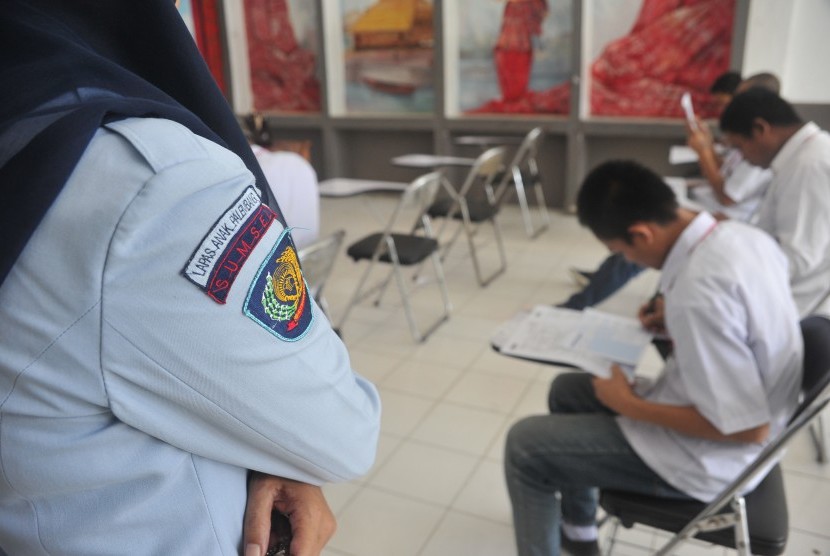 Petugas Lapas mengawasi anak didik Lapas yang mengerjakan soal Ujian Nasional hari pertama di Biklik Sekolah Filial Lapas Anak Palembang, Sumsel, Senin (18/5).