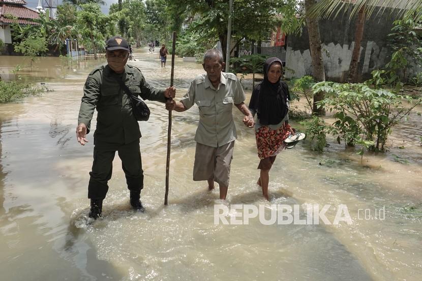 Petugas Linmas membantu mengevakuasi warga yang rumahnya terendam banjir\akibat hujan deras yang mengguyur wilayah Banyumas. 