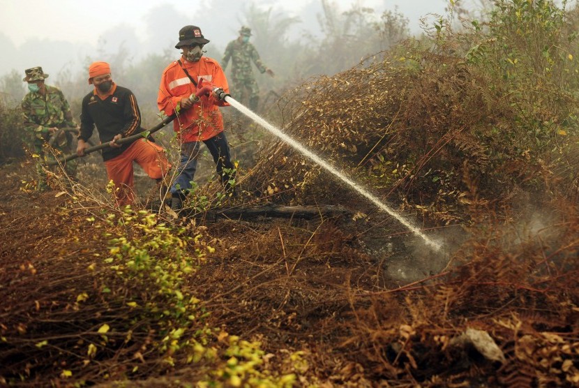 Petugas Manggala Agni dan TNI memadamkan sisa api yang membakar lahan gambut di Petaling, Muaro Jambi, Selasa (15/9).