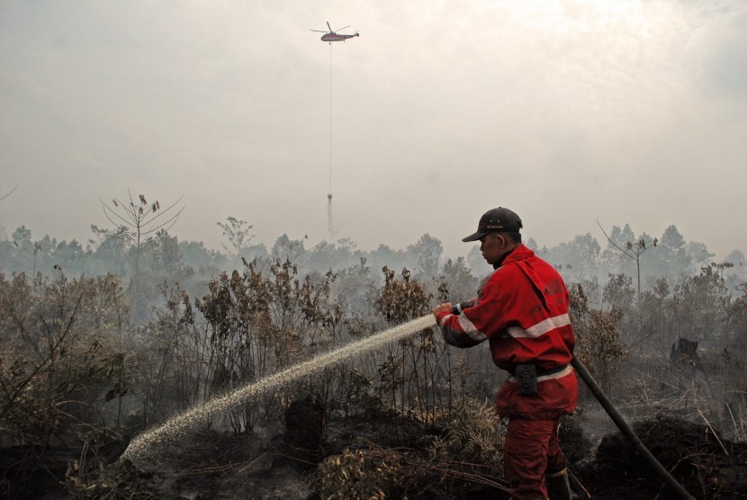  Petugas Manggala Agni dibantu Helikopter Badan Nasional Penanggulangan Bencana (BNPB) berusaha memadamkan api yang membakar lahan gambut di Pekanbaru, Riau, Senin (3/8).