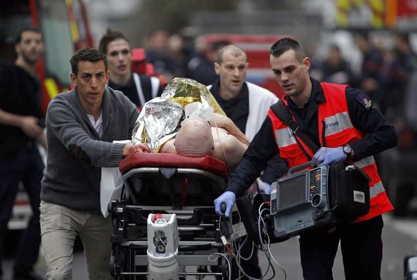 Petugas medik membawa korban yang terluka saat penembakan kantor majalah Charlie Hebdo di Paris, Prancis.