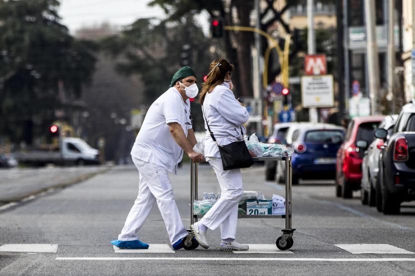 Petugas medis berjalan di Roma saat Italia tengah dilanda virus corona. Para ahli memperingatkan relaksasi lockdown dapat memicu bertambahnya penularan virus. Ilustrasi.