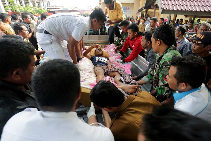 Petugas medis dibantu warga dan prajurit TNI berusaha mengangkat seorang korban gempa saat tiba di Rumah Sakit Umum Daerah (RSUD) Tgk Chik Ditiro Sigli di Pidie, Aceh, Rabu (7/12). 