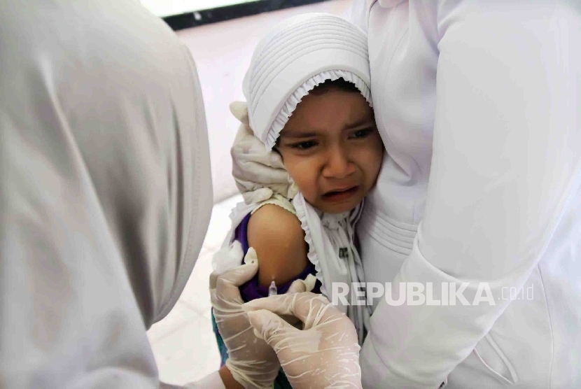 Petugas medis melakukan imunisasi kepada seorang anak. 