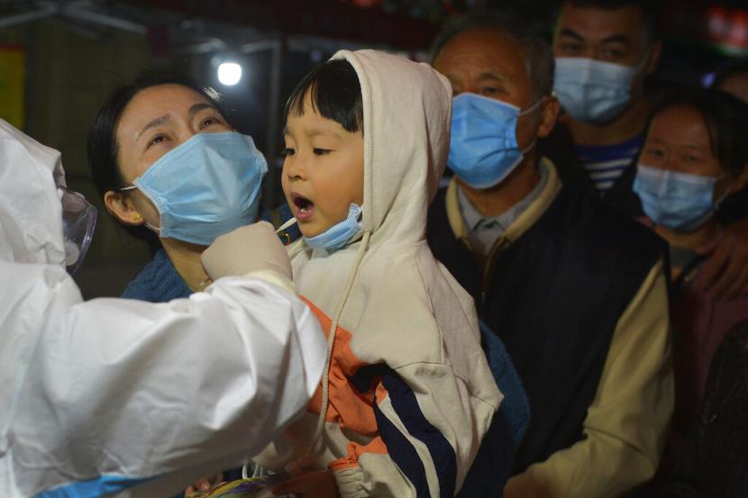 Petugas medis melakukan tes usap ke seorang anak di Qingdao, Provinsi Shandong, China, Selasa (13/10). China melaporkan jumlah tertinggi kasus Covid-19 tanpa gejala di Xinjiang. Ilustrasi. 