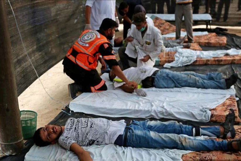 Petugas medis membantu warga Palestina yang ditembaki Israel.