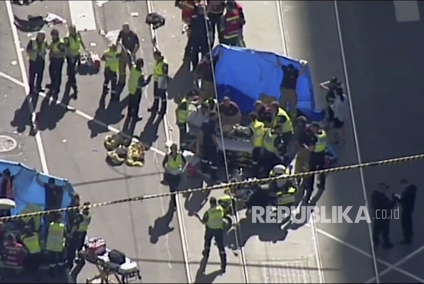 Petugas medis memberikan bantuan kepada korban yang tertabrak kendaraan di Melbourne, Australia. Kamis (21/12).  