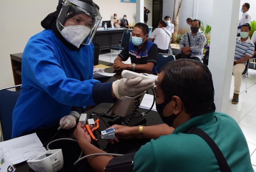 Petugas medis memeriksa suhu tubuh wartawan sebelum menerima suntikan vaksin COVID-19 Sinovac dosis kedua di Puskesmas Tawangrejo, Kota Madiun, Jawa Timur, Rabu (10/3/2021). Vaksinasi COVID-19 dosis kedua tersebut diikuti sekitar 50 wartawan sebagai upaya penanggulangan pandemi COVID-19.