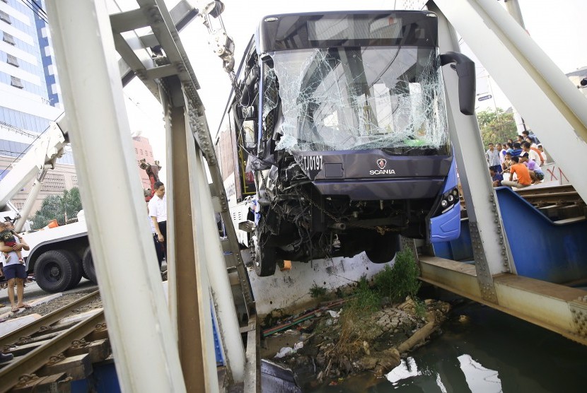 Petugas melakukan evakuasi bus Transjakarta yang mengalami kecelakaan di perlintasan kereta api Gunung Sahari, Jakarta, Kamis (19/5). 