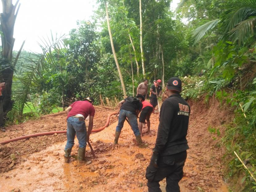 Petugas melakukan pembersihan material longsor yang menutup akses jalan di Desa Karanglayung, Kecamatan Karangjaya, Kabupaten Tasikmalaya, Kamis (10/11/2022).