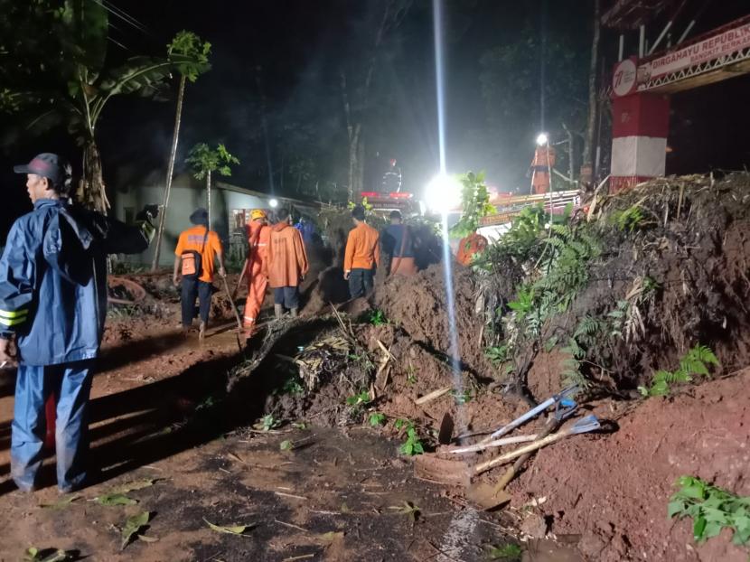 Petugas melakukan pembersihan material tanah longsor yang menutup akses jalan di Desa Puspahiang, Kecamatan Puspahiang, Kabupaten Tasikmalaya, Ahad (13/11/2022) malam. 