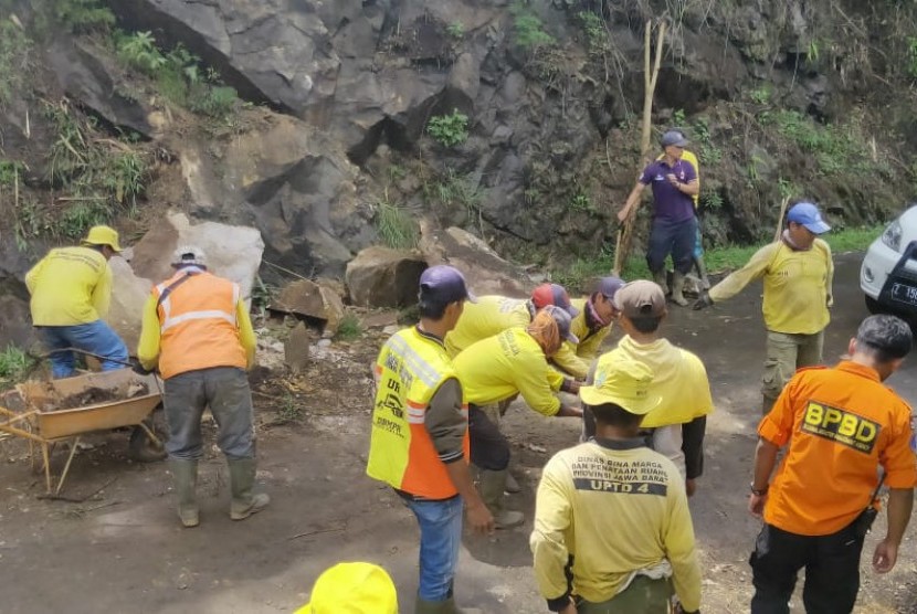 Petugas melakukan pembersihan sisa material longsor yang terjadi di jalan provinsi, tepatnya Kampung Sodong, Desa Keramatwangi, Kecamatan Cikajang, Kabupaten Garut, Senin (30/12). 