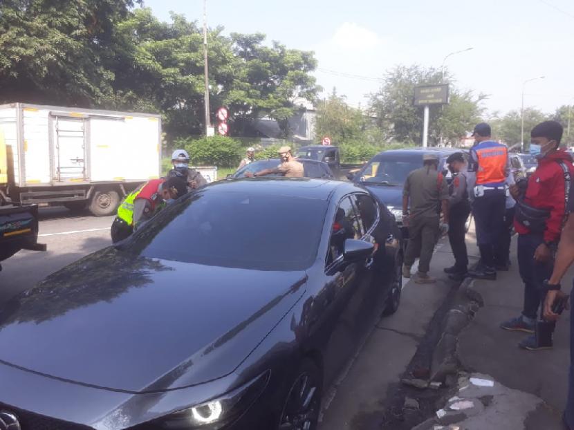 Petugas melakukan pemeriksaan dokumen perjalanan dan kesehatan terhadap pengendara mobil berpelat luar Bandung di gerbang keluar Tol Buah Batu Bandung. Belasan diantaranya diputar balik, Kamis (6/5). 