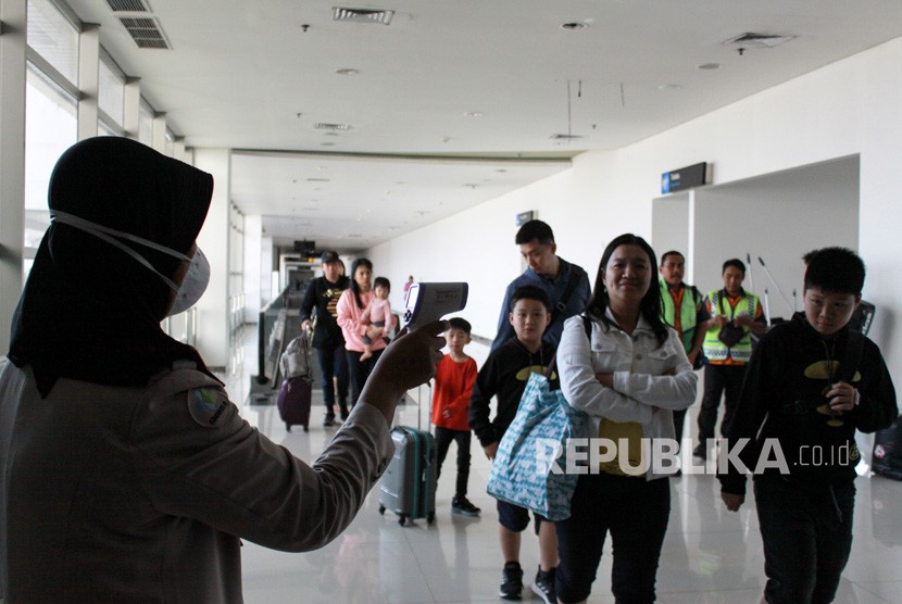 Petugas melakukan pendeteksi suhu tubuh (thermal scanner) saat penumpang pesawat tiba di terminal 2 Bandara Juanda Surabaya, Jawa Timur, Rabu (22/1/2020). 