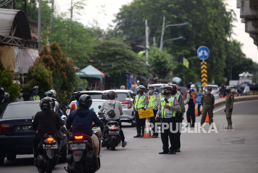 Petugas melakukan pengecekan kepada pengendara dengan plat nomor luar daerah yang melintasi Check Point PSBB di kawasan Kalimalang, Jakarta.