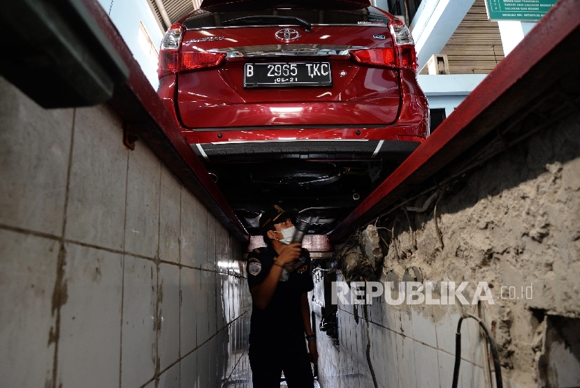 Petugas melakukan pengecekan saat uji uji kendaraan bermotor (KIR) Taksi berbasis aplikasi daring (online) di Pengelola Pengujian Kendaraan Bermotor, Pulo Gadung, Jakarta Timur, Senin (1/8).(Republika/Yasin Habibi)