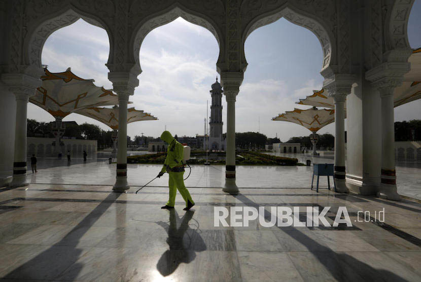   Petugas melakukan penyemprotan cairan disinfektan di komplek Masjid Baiturrahman, Banda Aceh, sebelum pelaksanaan ibadah shalat Jumat, (20/3).( EPA-EFE/Hotli Simanjuntak)(  Petugas melakukan penyemprotan cairan disin)
