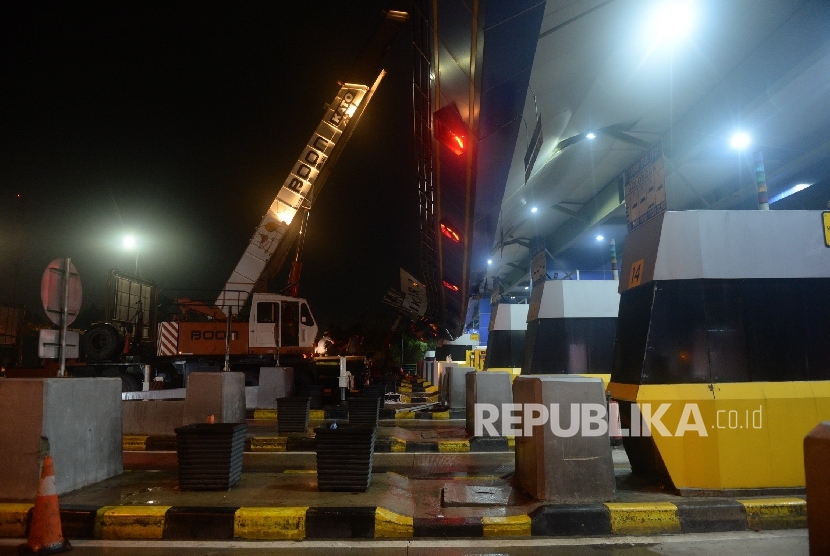 Petugas melakukan perbaikan atap gerbang Tol Cikunir 2 yang ambruk akibat hujan badai di Bekasi, Ahad (14/2) malam. (Republika/Yasin Habibi)