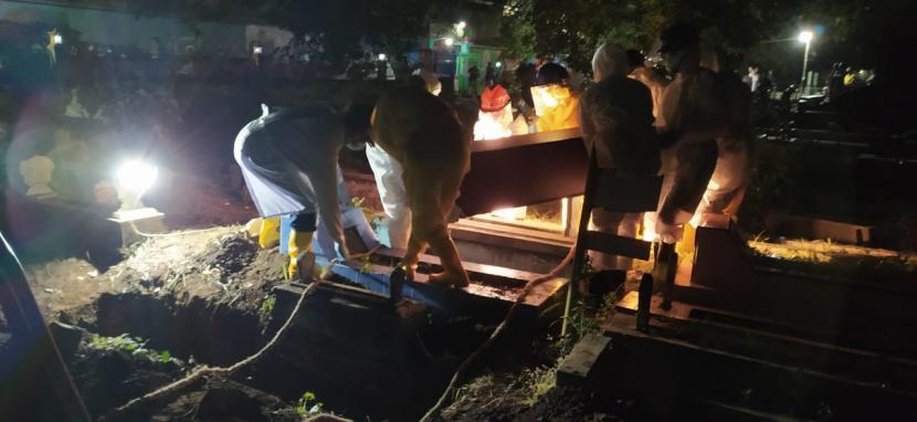 Petugas melakukan prosesi pemakaman jenazah Covid-19 di Kota Malang. 