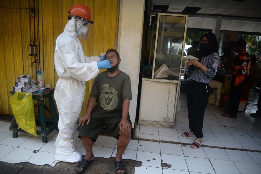 Petugas melakukan tes swab terhadap pedagang pasar.