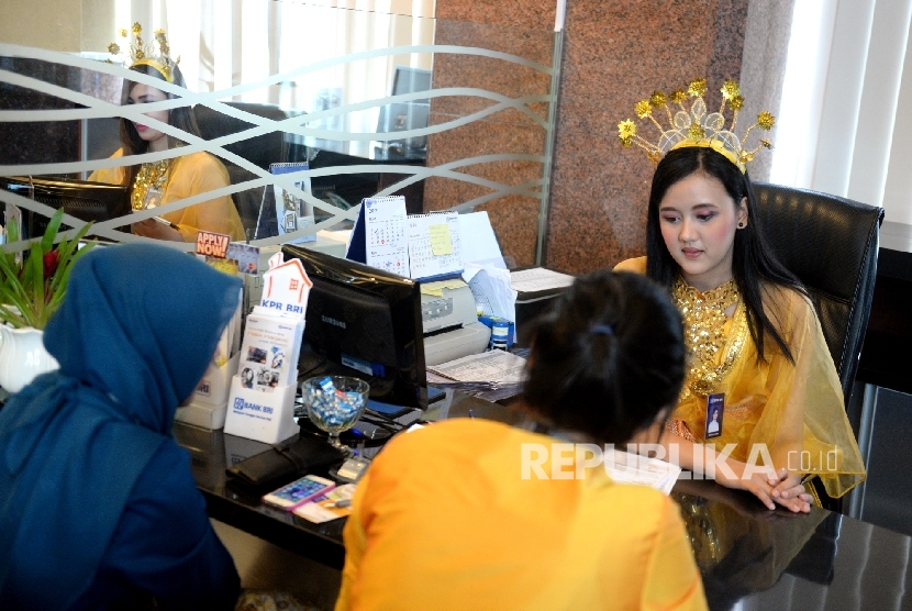 Petugas melayani nasabah menggunakan baju adat Bugis di Kantor Layanan Bank BRI, Jakarta, Jumat (21/4).