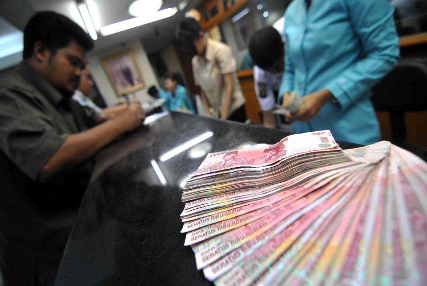 Petugas melayani penukaran mata uang di jasa penukaran uang, Jakarta, Rabu (18/6).