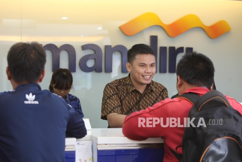 Petugas melayani penyetoran uang oleh nasabah di cabang Bank Mandiri Pertamina UPMS III, Jakarta, Rabu (28/6).