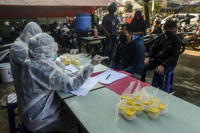 Petugas melayani warga yang akan menjalani tes Polymerase Chain Reaction (PCR) di perbatasan Jakarta-Bekasi, Lubang Buaya, Jakarta.