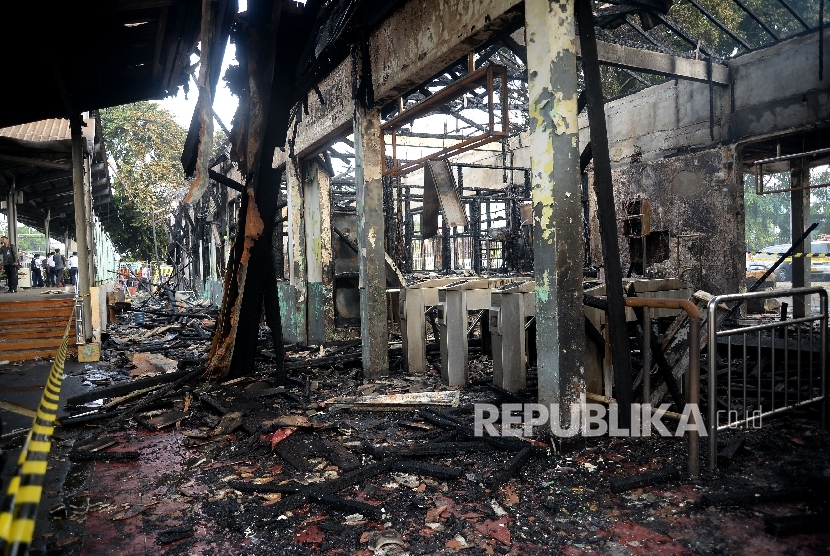  Petugas melintas di depan bangunan yang hangus terbakar di Stasiun Klender, Jakarta, Jumat (19/5).
