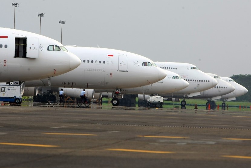 Petugas melintas di depan deretan pesawat Garuda Indonesia Boing 777 - 300ER.