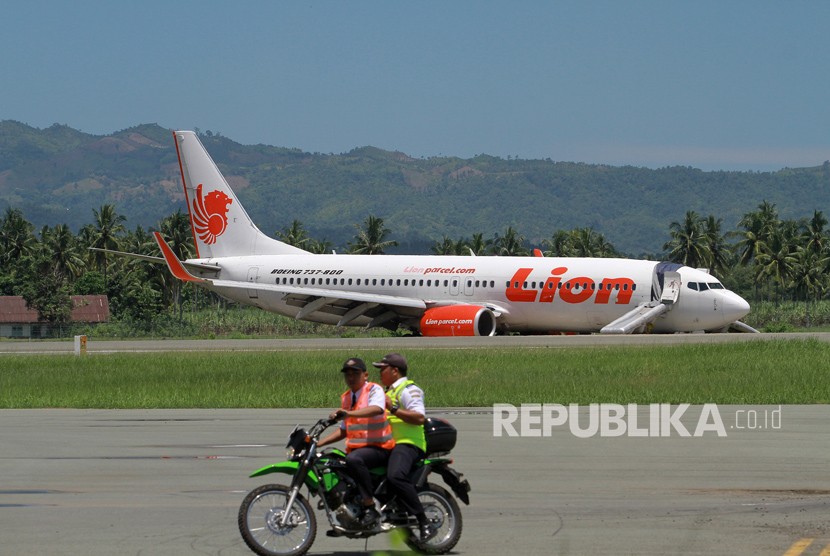 Petugas melintas di depan pesawat maskapai Lion Air yang berada di atas rerumputan bahu landasan pacu dengan kondisi roda pendaratan depan patah di Bandara Djalaludin, Kabupaten Gorontalo, Gorontalo, Senin (30/4).