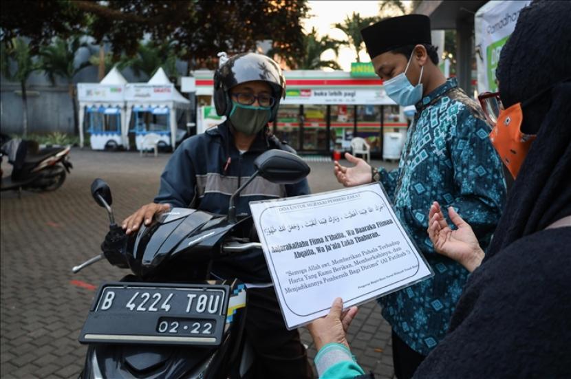 Petugas memakai masker mengumpulkan zakat fitrah dengan layanan drive-thru sebagai langkah pencegahan penyebaran pandemi virus korona di Masjid Nurul Hidayah di Jakarta, Indonesia pada tanggal 11 Mei 2021.