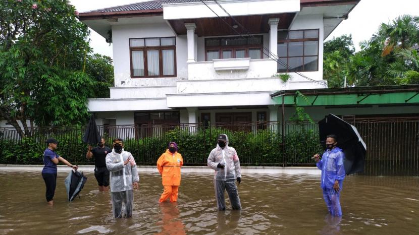 Petugas memantau banjir yang terjadi di jalan di depan rumah Kapolri Listyo Sigit Prabowo di Kelurahan Bangka, Kecamatan Mampang Prapatan, Jakarta Selatan, Kamis (18/2) siang.