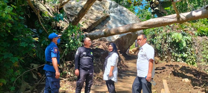 Petugas memantau kondisi jalan desa yang terutup batu berukuran besar di Desa Kawasen, Kecamatan Banjarsari, Kabupaten Ciamis, Rabu (29/6/2022). Saat ini, jalan tersebut hanya bisa dilalui kendaraan roda dua.