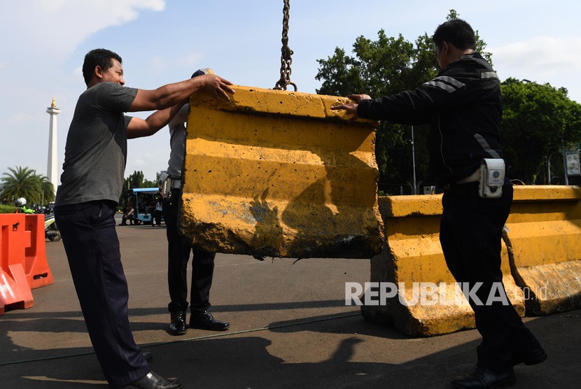 Petugas memasang beton pemisah jalan atau Moveble Concrete Barrier (MCB) di depan Istana Merdeka Jakarta, Kamis (14/2/2019). 