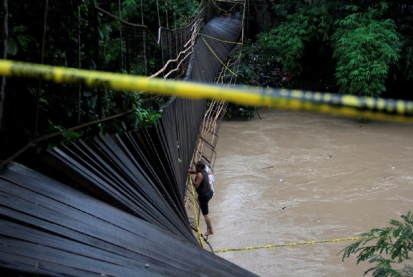 Petugas memasang garis polisi di jembatan gantung yang roboh di Kampung Pekarungan, Serang, Banten, Selasa (21/1).