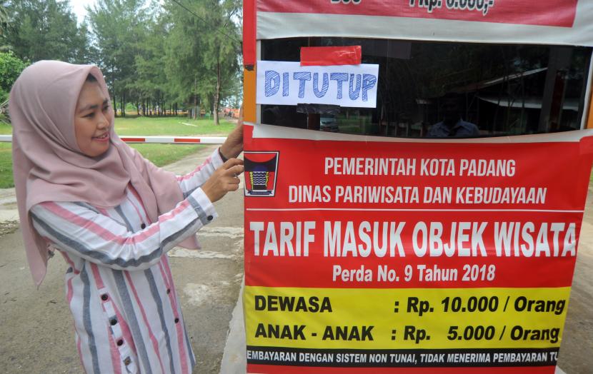 Petugas memasang pengumuman tanda ditutupnya objek wisata Pantai Air Manis, di Padang, Sumatera Barat, Jumat (20/3/2020).