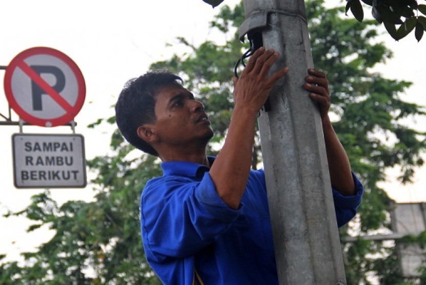 Petugas memasang pipa pengaman kabel tiang lampu untuk Penerangan Jalan Umum (PJU) di Jalan Bekasi Timur, Jakarta Timur, Selasa (29/10).