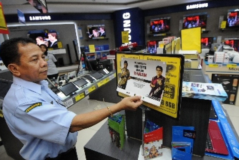 Petugas memasang poster kampanye antipembajakan perangkat lunak di salah satu toko elektronik di Mal Taman Anggrek, Jakarta.