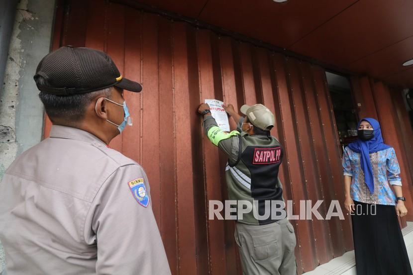 Petugas memasang stiker himbauan menutup tempat usaha non esensial saat razia di Jalan Doho, Kota Kediri, Jawa Timur, Jumat (16/7/2021). Razia di pusat pertokoan tersebut guna memastikan penerapan Pemberlakuan Pembatasan Kegiatan Masyarakat (PPKM) Darurat berjalan dengan baik guna memutus mata rantai penyebaran COVID-19. 