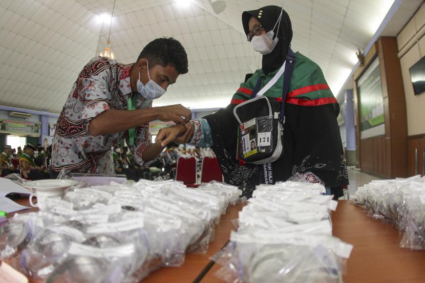 Petugas memasangkan gelang identitas kepada seorang calon haji kelompok terbang (kloter) pertama embarkasi Batam di Asrama Haji Batam, Kepulauan Riau, Selasa (14/6/2022). Dua Kloter Jamaah Haji Riau Sudah Berada di Madinah