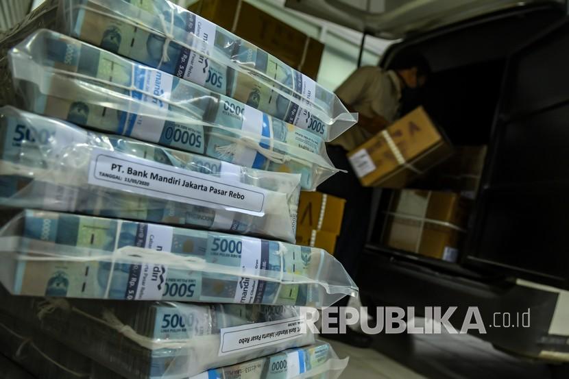 Petugas memasukan kardus berisi uang pecahan rupiah ke dalam mobil untuk didistribusikan dari Cash Center Mandiri, Jakarta, Senin (11/5/2020).