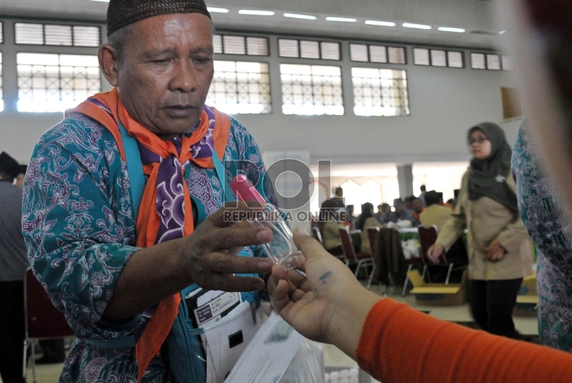 Petugas membagikan botol semprot (spray) kepada calon jamaah haji di Asrama Haji Pondok Gede, Jakarta, Kamis (28/8). Botol berisikan air ini bisa digunakan jamaah agar terhindar dari dehidrasi.